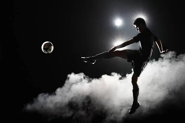 Fotografie Soccer player kicking the ball at night on stadium, Stanislaw Pytel